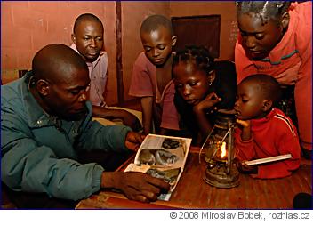 Laurent Tsiobiandjeuh si při světle petrolejky čte z knížky gorilích pohádek